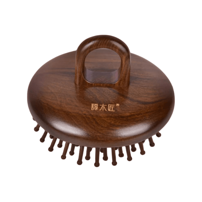 チャイナ・タン・カーペンターは、丸いエアクッションの木製櫛を使って頭皮をマッサージし、抜け毛を和らげます。
